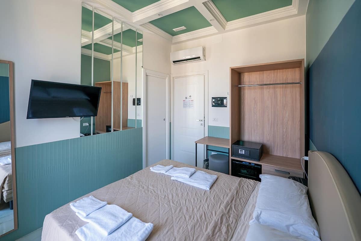 Une chambre d’hôtel avec un lit, une télévision, un bureau et un miroir.