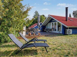 A modern house with a red roof, a patio with outdoor furniture, and a large window overlooking the yard. - "Lycka" - 700m from the sea by Interhome (Væggerløse)