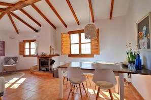 A dining area with a table, chairs, a fireplace, and large windows. - Country House 'La Perla Andaluza' with Mountain View, Wi-Fi, and Air Conditioning (Alcaucin)
