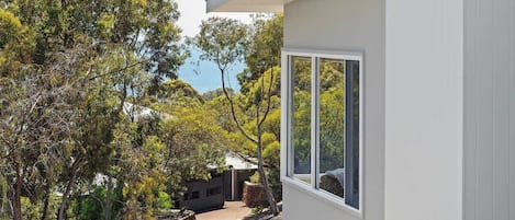 Ett modernt hus med ett stort fönster, omgivet av träd och med fri utsikt över himlen.