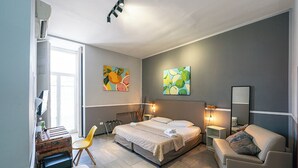 A modern bedroom with a bed, bedside tables, a chair, and artwork on the walls. - GREROS TOLEDO H. by Clapa Group dislocated hospitality (Naples)