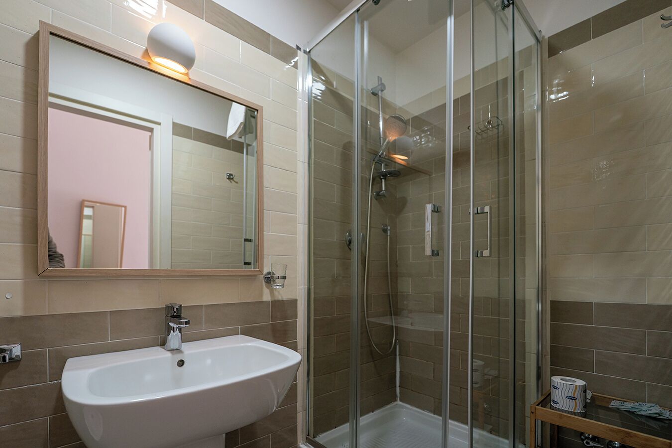 A modern bathroom with a glass-enclosed shower, a white sink, and a large mirror.