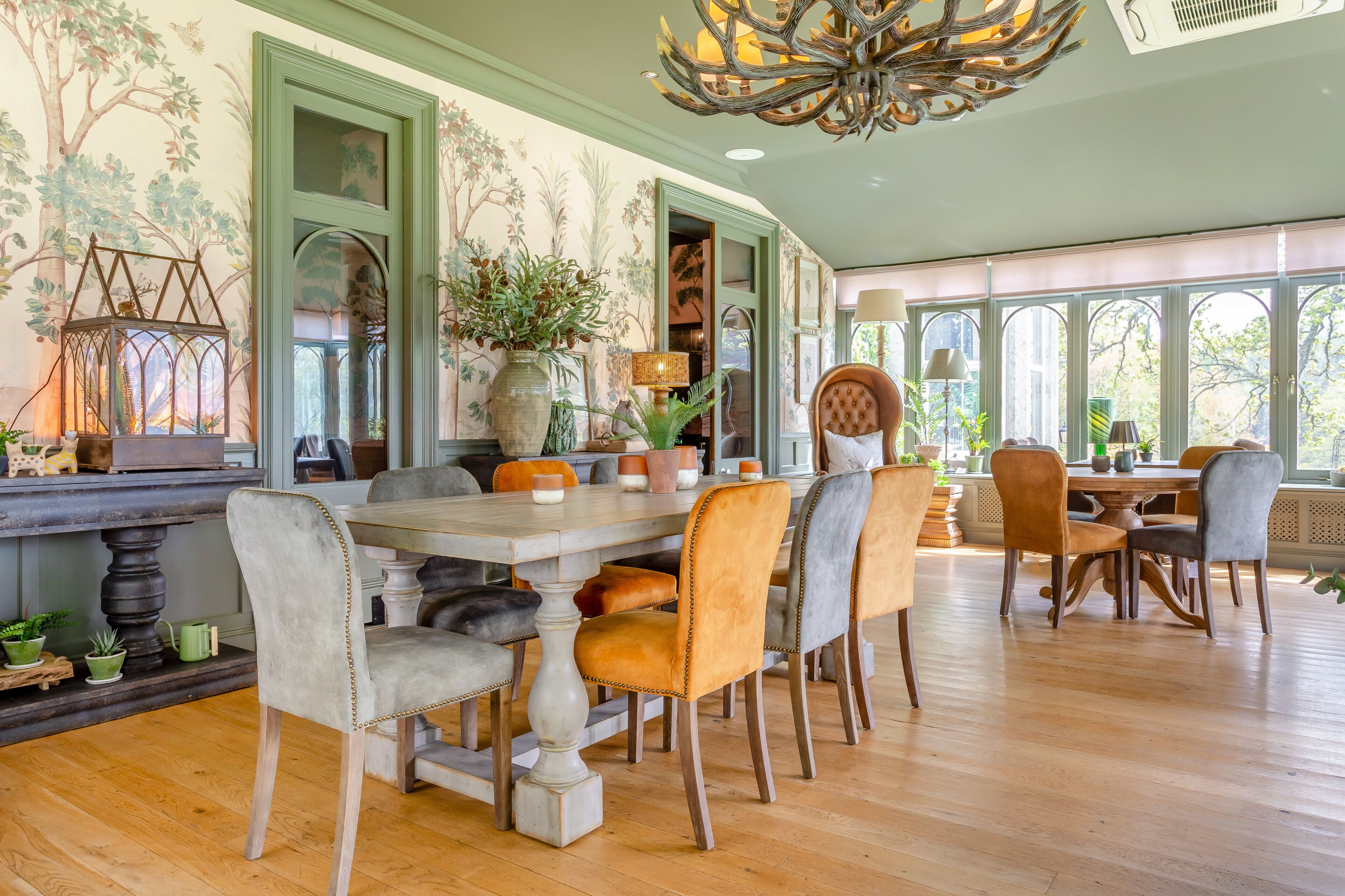 A dining area with a wooden table, upholstered chairs, and a chandelier.