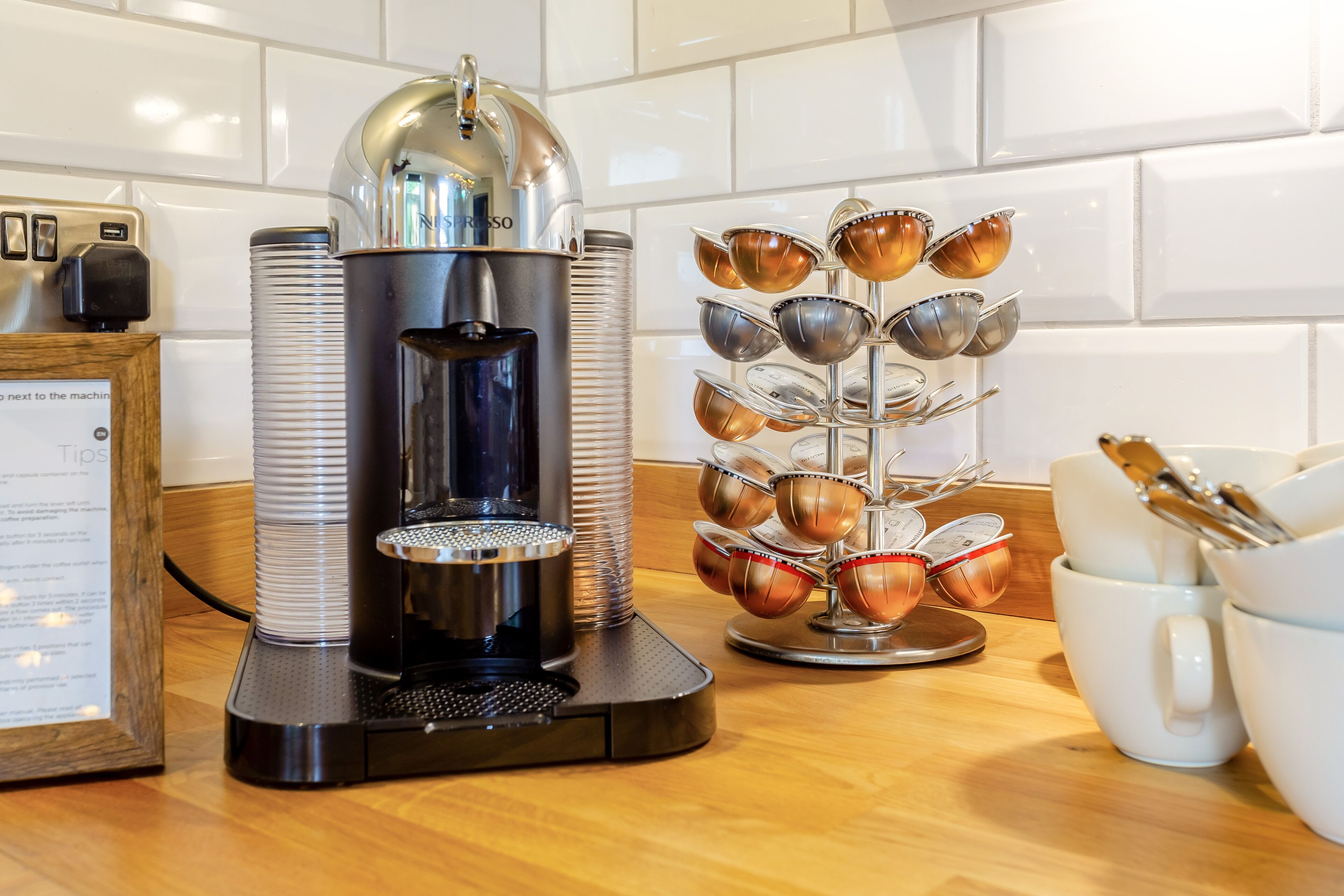 Een koffieapparaat met een opvangbak, een koffiekan en een kopjesrek met meerdere kopjes.