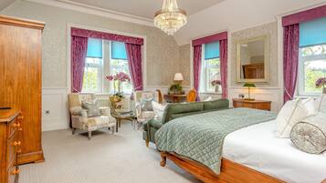 A bedroom with a bed, two chairs, a dresser, a mirror, and a chandelier.