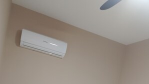 Una camera d'albergo con un letto, cuscini, un asciugamano arrotolato e una ventola a soffitto.