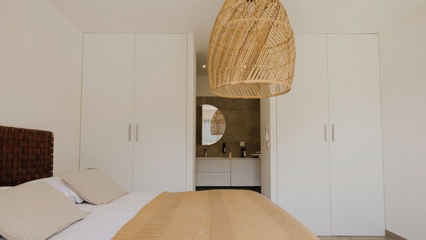 Une chambre à coucher avec un lit, un grand miroir et une armoire.