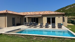 Une maison avec une piscine, un espace salon extérieur et une vue sur une colline.