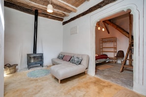 Une pièce chaleureuse avec un canapé, une petite table, une lampe, une échelle et une cheminée.