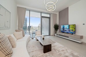 Uma sala de estar moderna com um sofá, uma mesa de centro, uma TV em um suporte e uma janela grande com vista para a cidade.