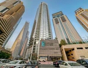 A high-rise building with a prominent 'LIV' sign, surrounded by other tall buildings. - Luxury 1BR LIV Marina Modern with Marina View (Dubai)