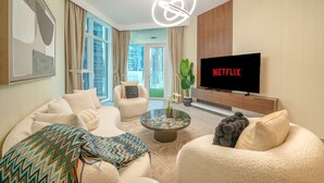 Una sala moderna con sofá, sillón, mesa de centro y un televisor que muestra 'NETFLIX'.