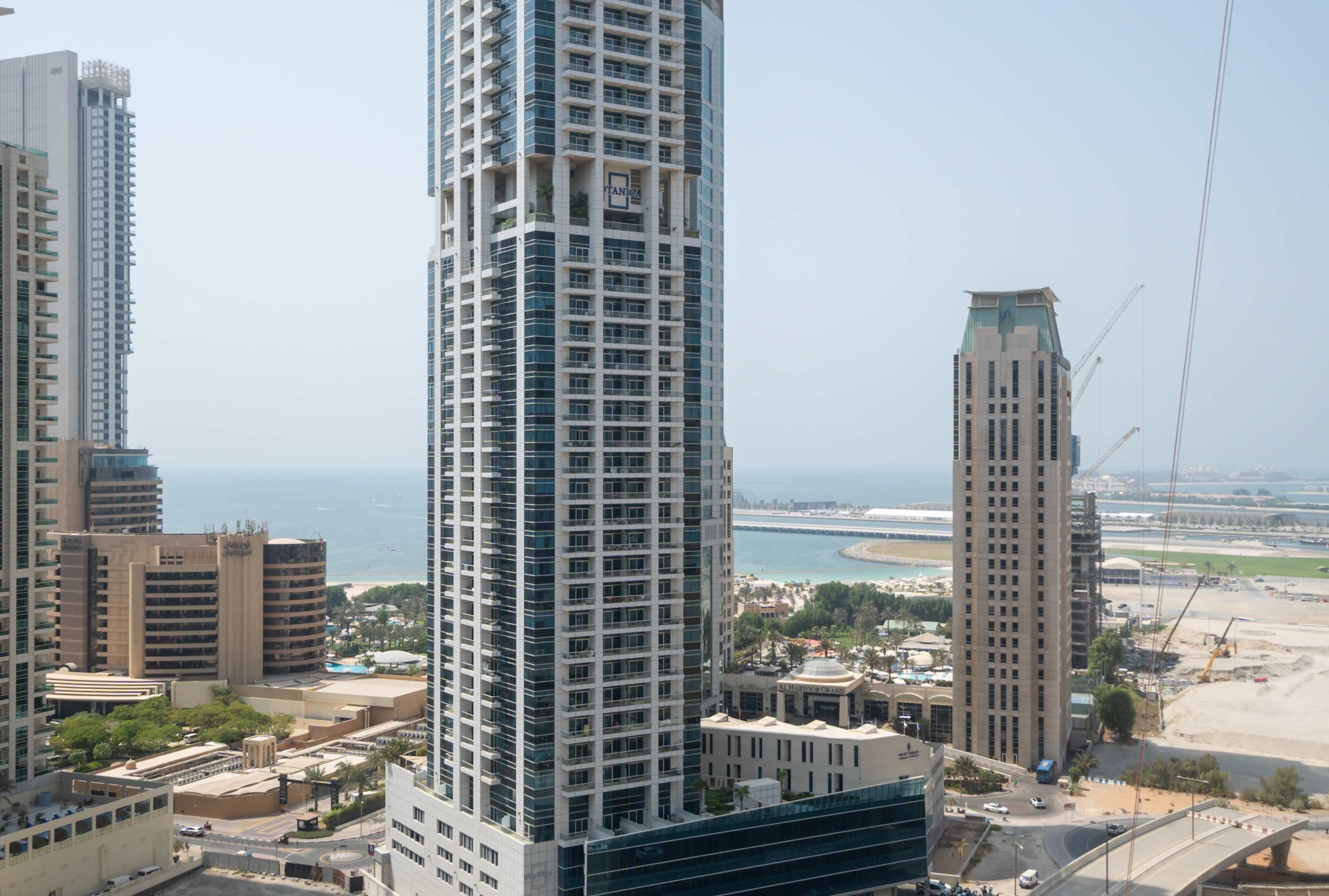 Un edificio alto con varios pisos, amplias ventanas y vista al litoral.