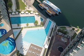 Ein Pool auf dem Dach mit mehreren Bereichen, eine Marina mit Booten und Blick auf die umliegenden Gebäude.