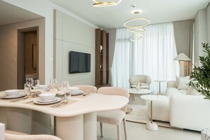 Un salon moderne comprenant un coin repas, un ensemble de canapés et un téléviseur fixé au mur.