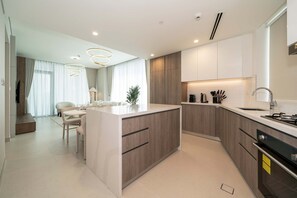 A modern kitchen with a central island, built-in appliances, and a dining area with a sofa and table. - Experience 2BR Luxury Living at in LIV Marina (Dubai)