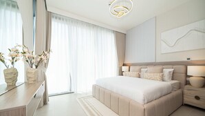 Ein modernes Schlafzimmer mit einem großen Bett, Nachttischen, einem Spiegel und Blick ins Freie.