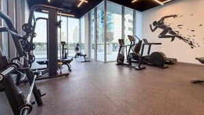 Ein Fitnessstudio mit verschiedenen Trainingsgeräten, großen Fenstern und Wandgemälden.