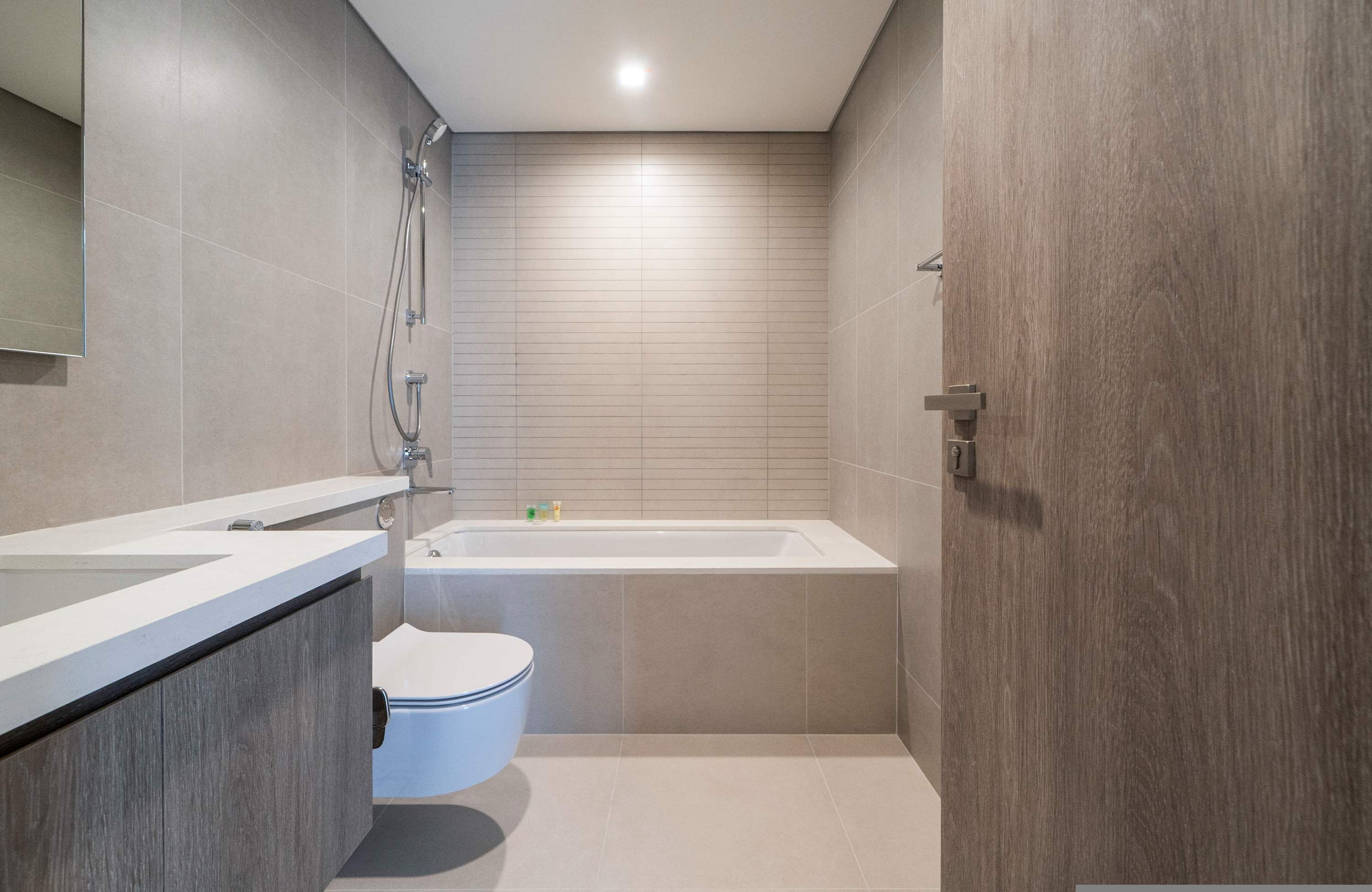 A modern bathroom with a bathtub, toilet, and vanity.