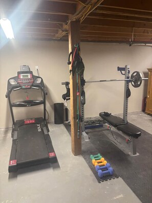 Ein Heimfitnessraum mit Laufband, Langhantelbank und Gewitterregal.