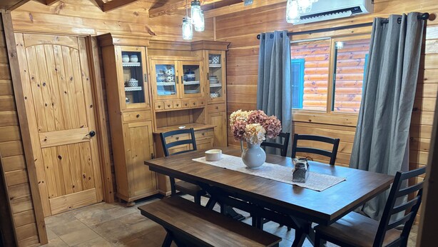 Ein Esszimmer mit Holztisch, Stühlen, Bänken und Schränken.