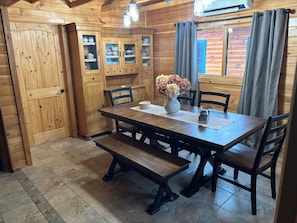 A wooden dining room with a table, chairs, benches, and cabinets. - Luxurious Lakefront Log Home with Private Dock and fenced in yard (Augusta)
