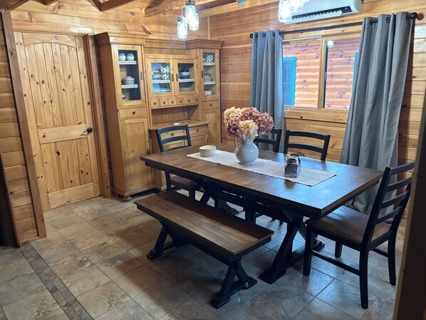Een eetkamer met een houten tafel, stoelen, banken en kasten.