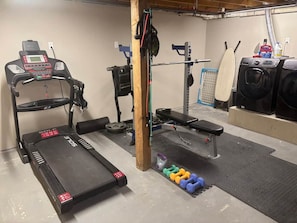 A home gym with a treadmill, bench, weight rack, and dumbbells. - Luxurious Lakefront Log Home with Private Dock (Augusta)