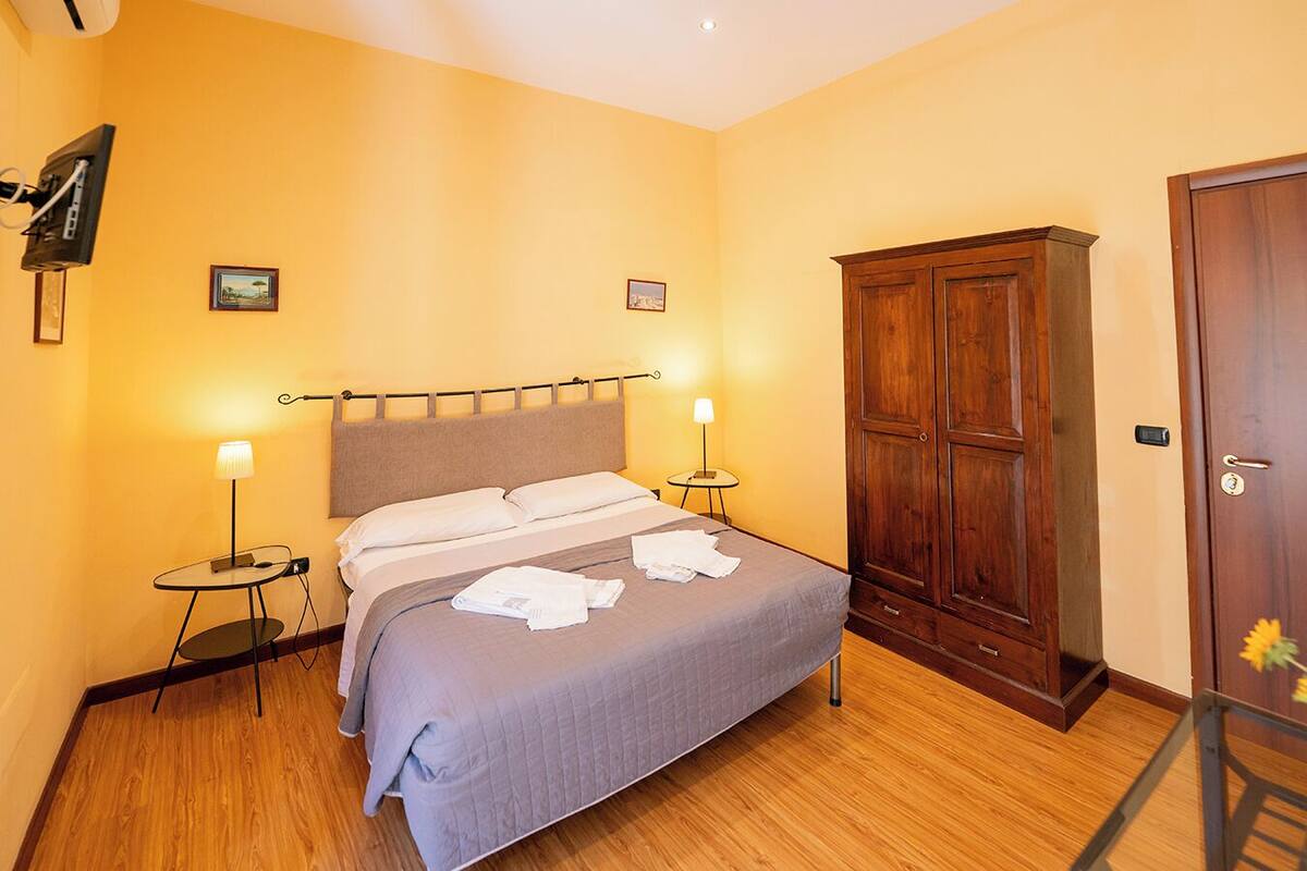 A bedroom with a bed, bedside tables, a wardrobe, and a door.