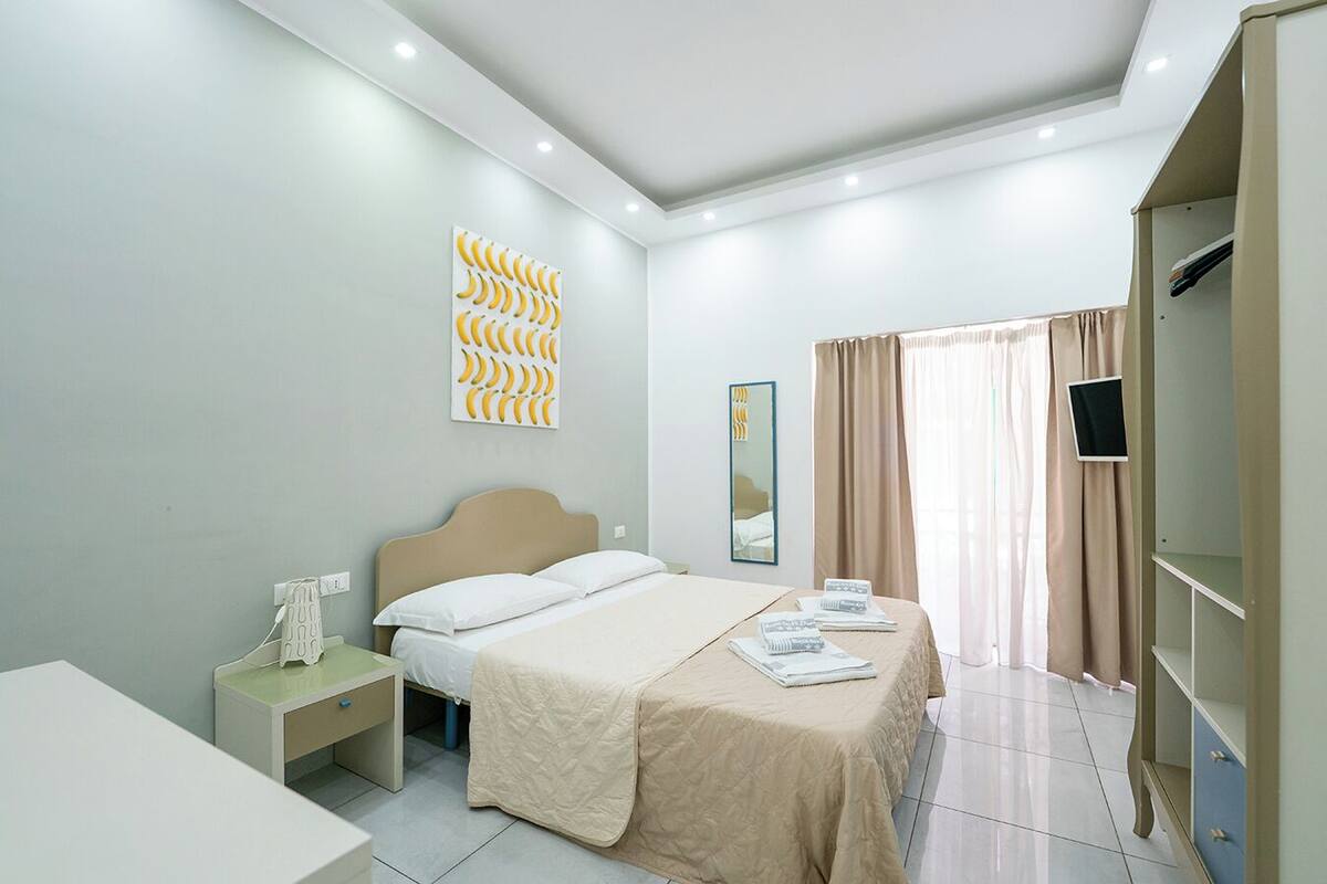 A modern bedroom with a bed, bedside tables, a wardrobe, and a wall art piece.
