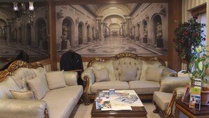 Amplia sala de estar con un mural grande, dos sofás, una mesita de centro con revistas y una planta en maceta.