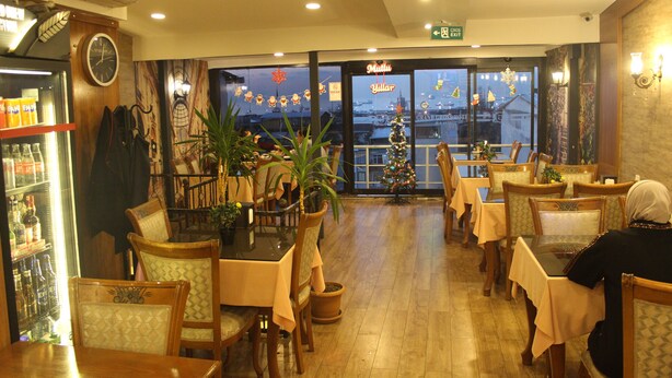Un restaurante con mobiliario de madera, un árbol de Navidad y vistas a la ciudad desde la ventana.