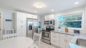 Una cocina moderna con armarios blancos, electrodomésticos de acero inoxidable y encimera de granito.