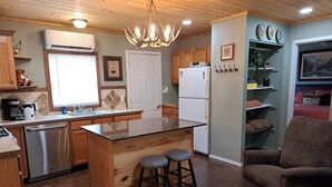 A kitchen with wooden cabinets, a stainless steel dishwasher, a white refrigerator, and a central island with stools.