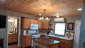 A kitchen with wooden cabinets, a microwave, a stove, and a chandelier.