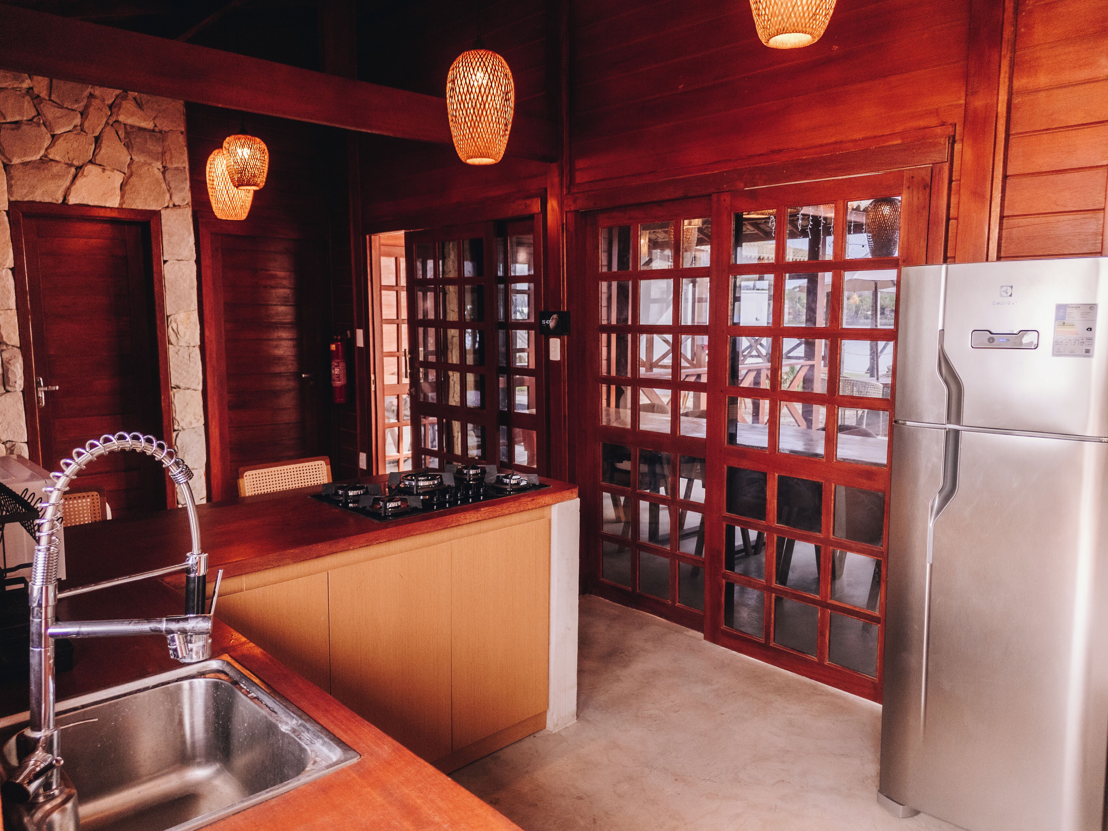 A kitchen with wooden cabinets, a stainless steel sink, a gas stove, and a refrigerator.