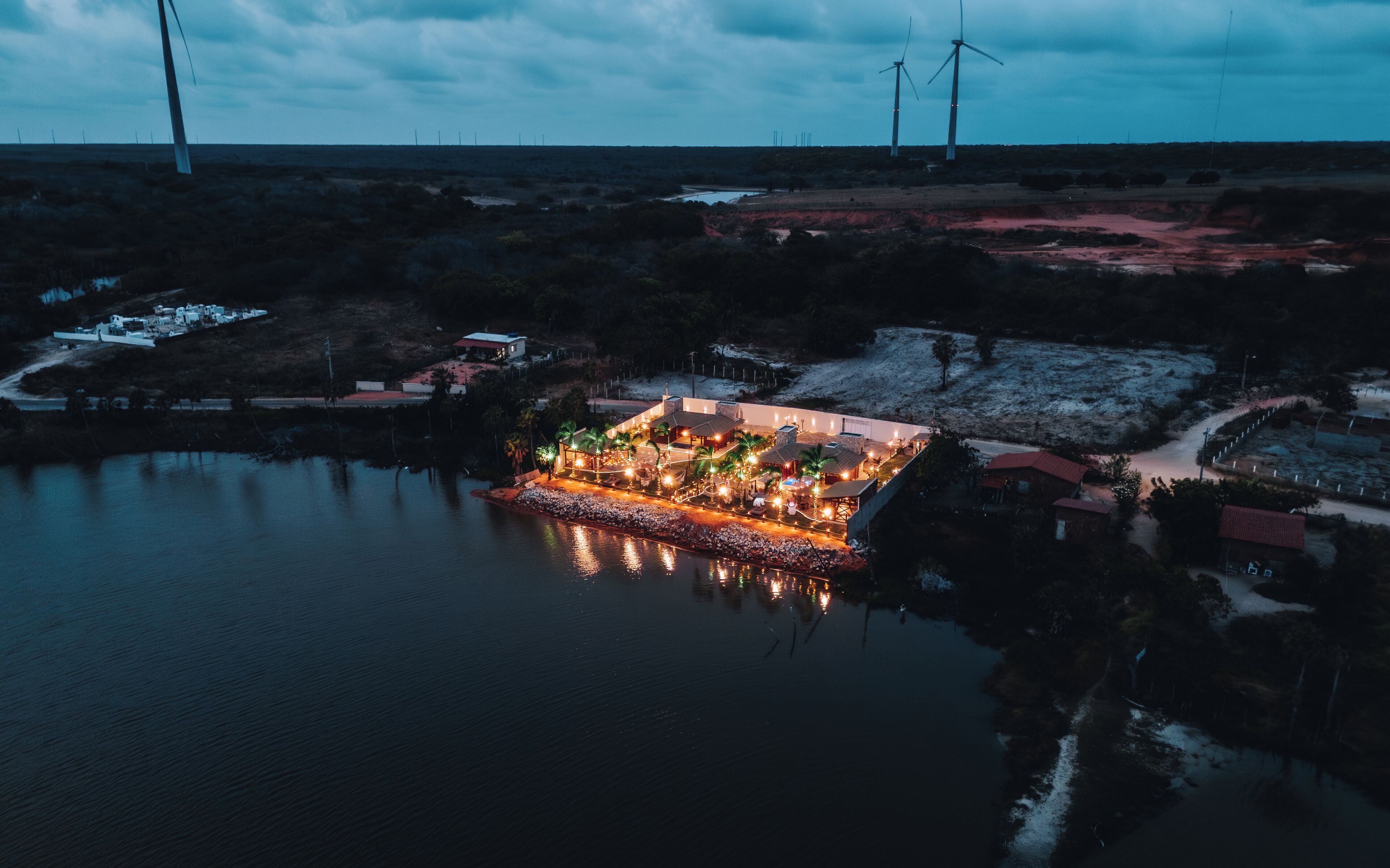A resort with a pool, outdoor lighting, and wind turbines in the background.