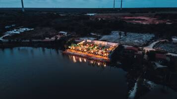 A resort with a pool, outdoor lighting, and wind turbines in the background.