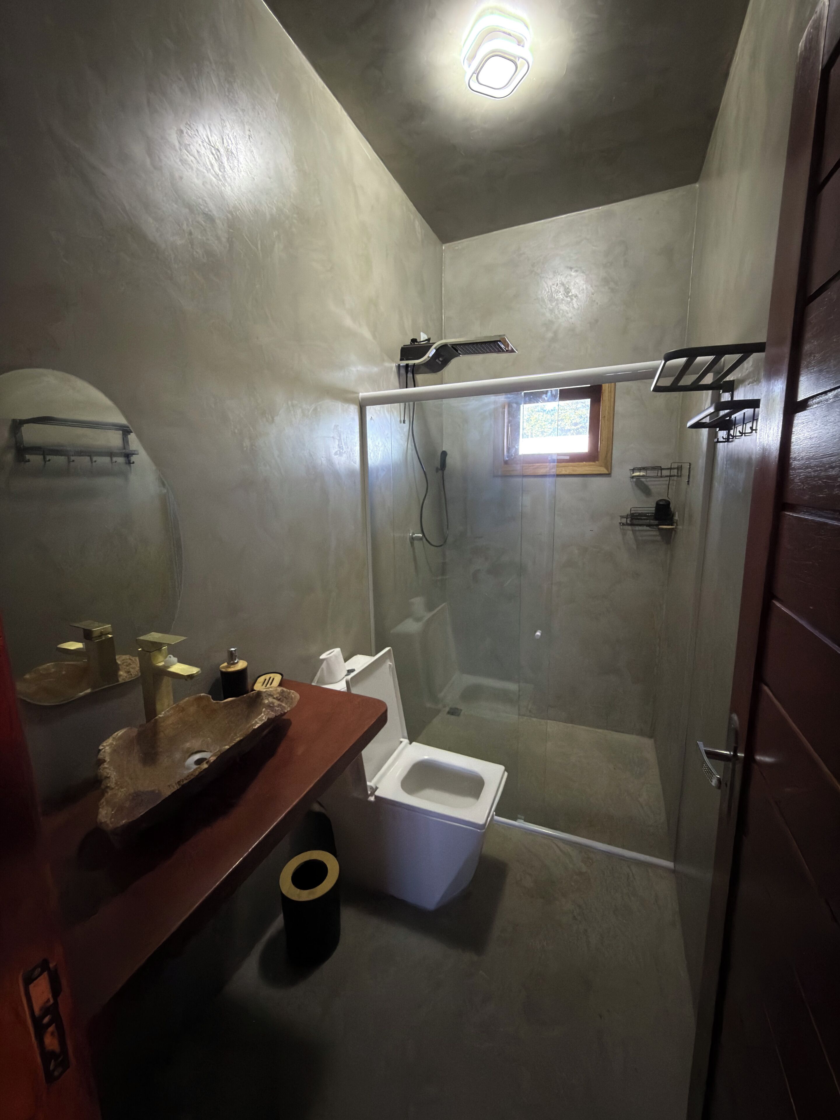 A bathroom with a glass-enclosed shower, a wooden vanity with a bowl sink, and a toilet.