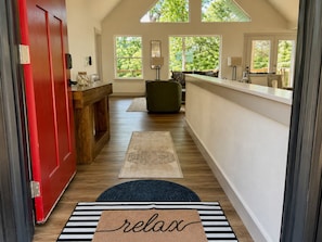 A hallway with a red door, a bench, a reception desk, and a rug with 'relax' written on it. - 9BR Theater Room Retreat: Dock Slip in cove, Sleeps 30! EV charger! (Lafollette)