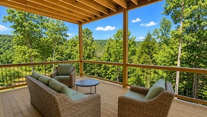 A covered deck with wicker furniture and a view of a forest. - 25% late summer discount!  9BR Theater Room Dock Slip in cove, Sleeps 30! (Lafollette)
