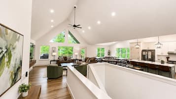 A spacious loft with a high ceiling, large windows, a kitchen with modern appliances, and a dining area.