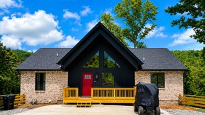 A two-story building with a red door, large windows, and a covered outdoor grill. - 25% late summer discount!  9BR Theater Room Dock Slip in cove, Sleeps 30! (Lafollette)