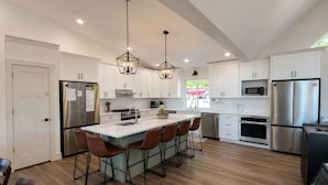 A modern kitchen with white cabinets, stainless steel appliances, a central island with bar stools, and pendant lighting. - 25% late summer discount!  9BR Theater Room Dock Slip in cove, Sleeps 30! (Lafollette)