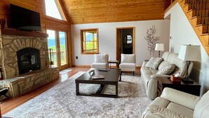 Ein geräumiges Wohnzimmer mit einem Steinkamin, einer Couch, einem Couchtisch und einer Treppe.