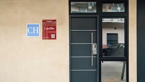 Entrada de un edificio con una puerta negra, un letrero con las letras 'CH' y 'Castillo', y un código QR.
