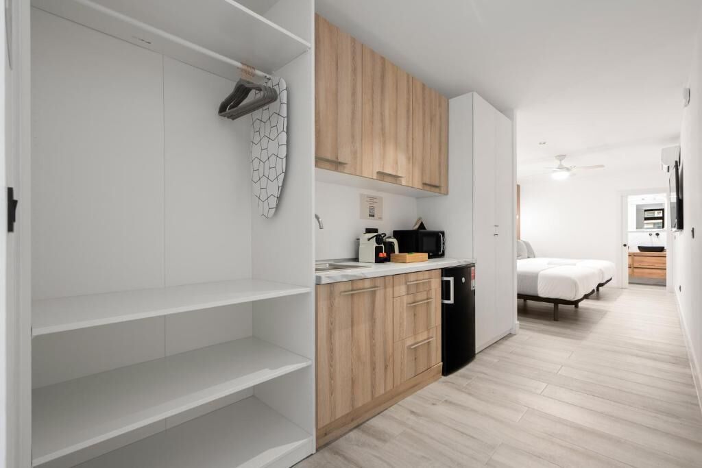 A compact kitchen with wooden cabinets, a countertop, and a dishwasher.