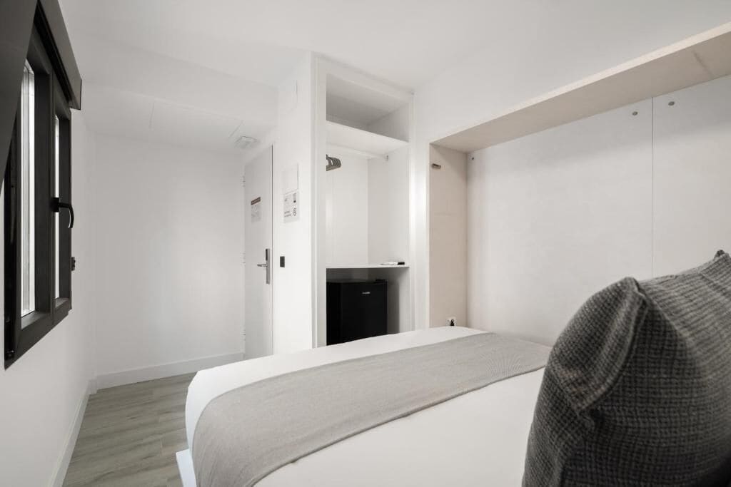 A bedroom with a bed, a wardrobe, and a door leading to another room.