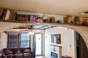 A cozy living room with a leather sofa, a fireplace, and a bookshelf with books and decorative items. - Historic Family Escape Near Downtown, Romantic + Pet-Friendly (Wilmington)