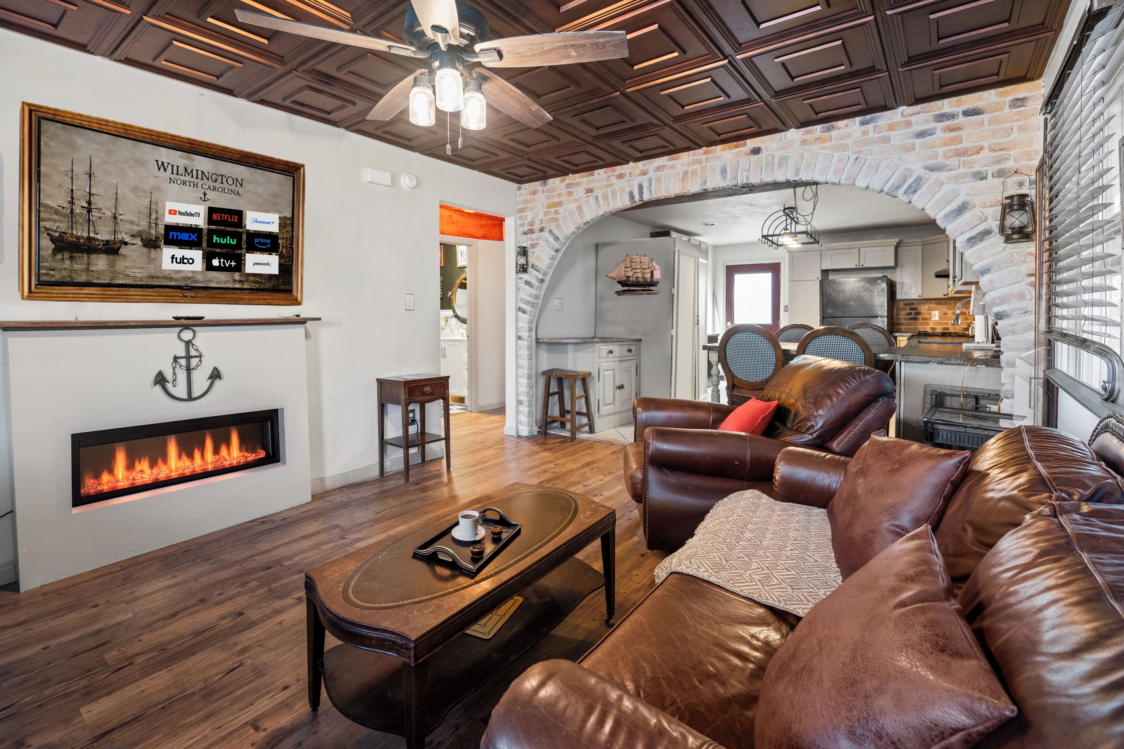 A living room with a fireplace, leather sofa, and a ceiling fan.